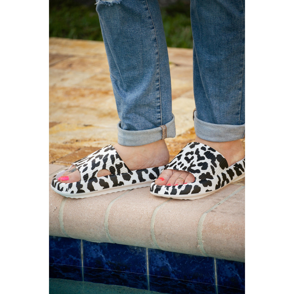 White leopard-print beach slides with a bold spotted pattern and easy slip-on design